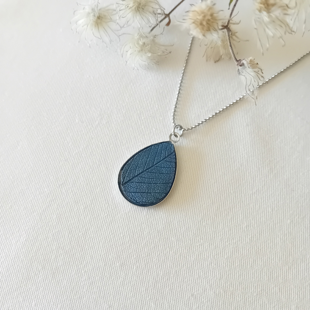 collier a planter par modibulle, sur chaine en acier inox, cabochon en forme de goutte de goutte de couleur bleu de prusse, contenant des graines d'ancolies des jardins