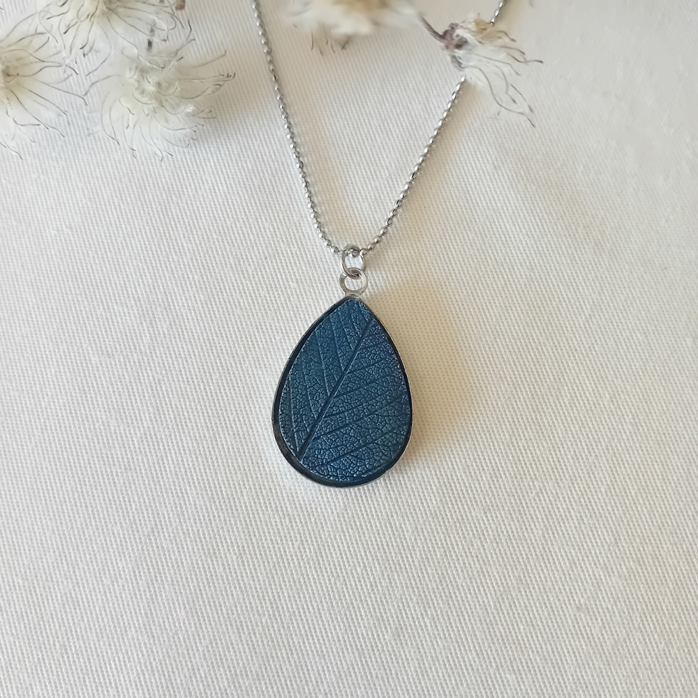 collier a planter par modibulle, sur chaine en acier inox, cabochon en forme de goutte de goutte de couleur bleu de prusse, contenant des graines d'ancolies des jardins