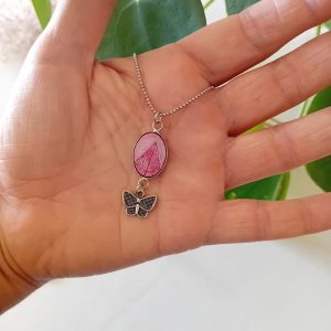 Un collier à planter par Modibulle, avec sa perle contenant des graines de phacélie de couleur rose et sa breloque papillon